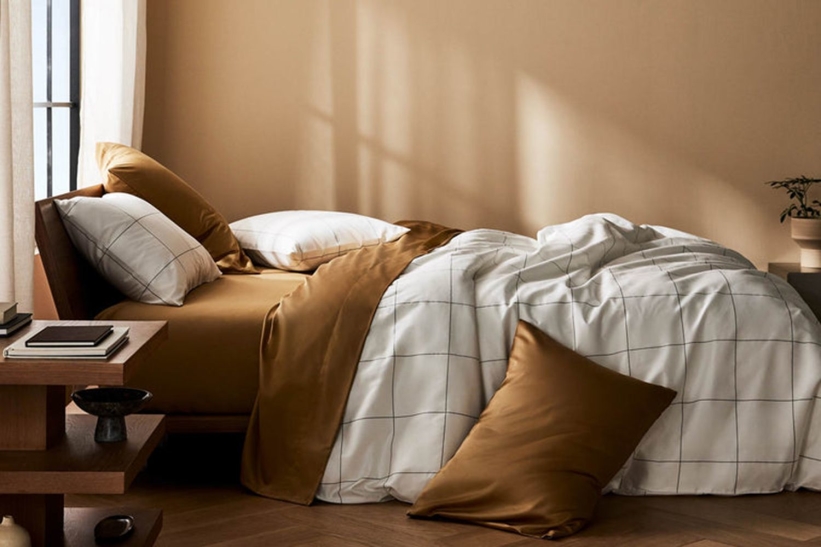Modern bedroom with brown and white bedding and wooden furniture.