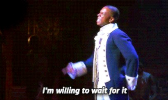 Actor in a historical costume performing on stage with caption 'I'm willing to wait for it'.