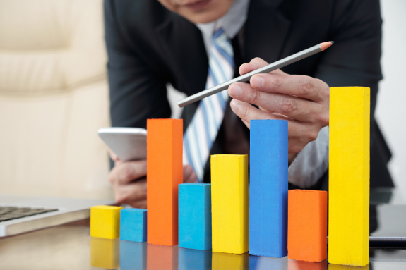 Businessman analyzing colorful bar graph on office desk.