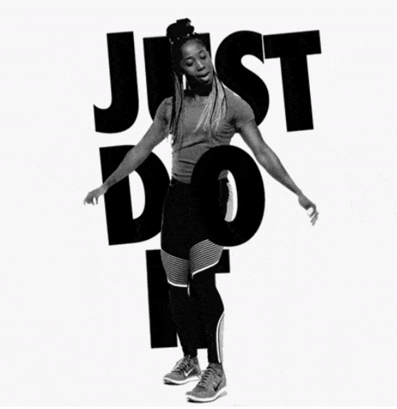 Woman in sporty attire dancing in front of 'Just Do It' text
