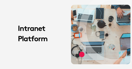 Top view of a work desk with laptops, phones, and office supplies for intranet platform.