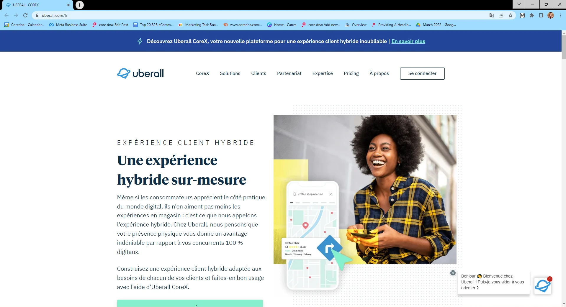 Smiling woman in plaid shirt holding a smartphone with Uberall CoreX hybrid experience text.