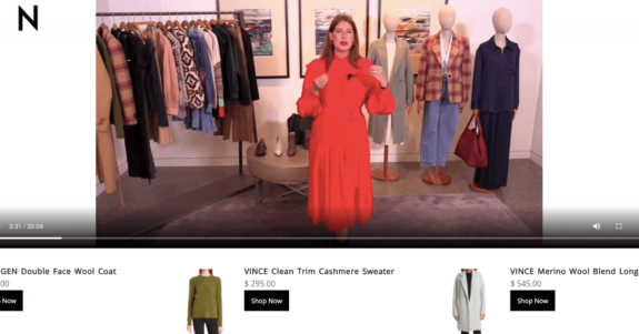 Woman in red dress presenting fashion showroom with clothing rack and mannequins.