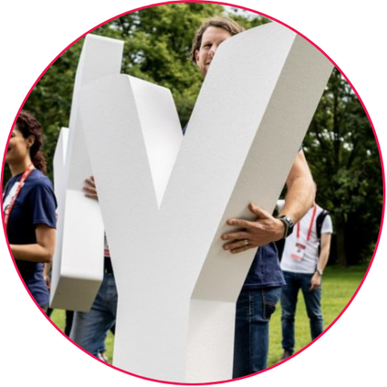 Group of people holding large white letters at an outdoor event.