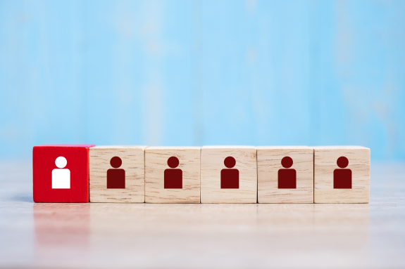 Red block with white icon among wooden cubes with brown icons on a blue background.