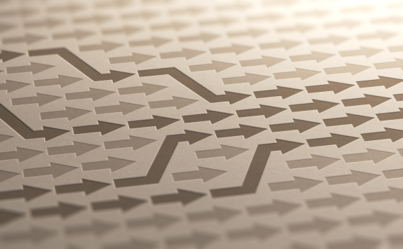 Zigzag pattern of arrows in a 3D embossed style on a beige surface.
