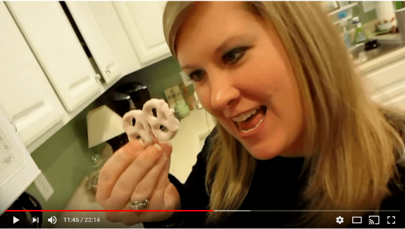 Woman holding yogurt-covered pretzels in a kitchen.