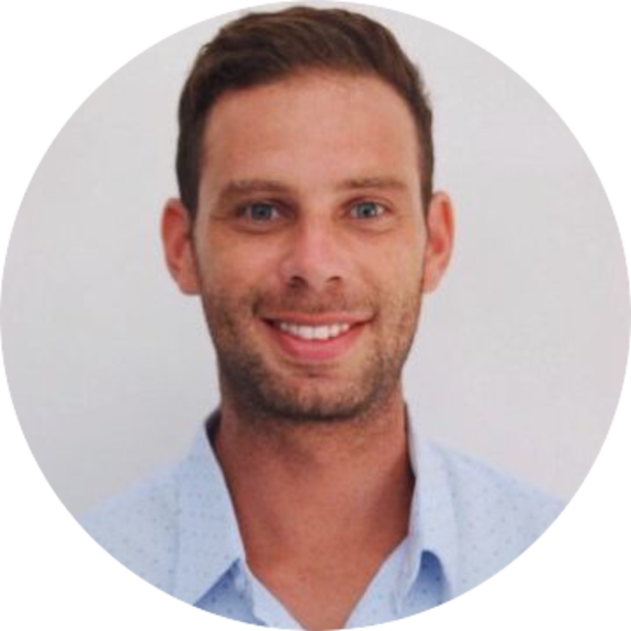 Smiling man in a blue shirt against a plain background
