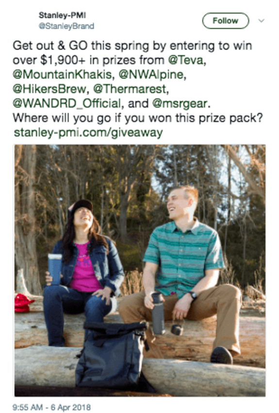 A couple enjoying a picnic in a spring forest with backpacks and mugs.