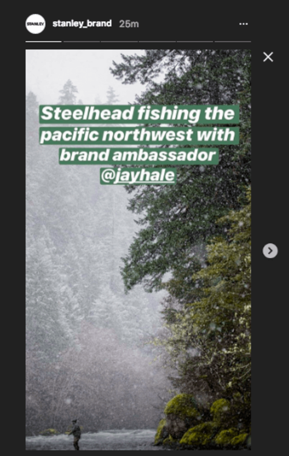 Person fishing in a snowy river in the Pacific Northwest surrounded by forest.