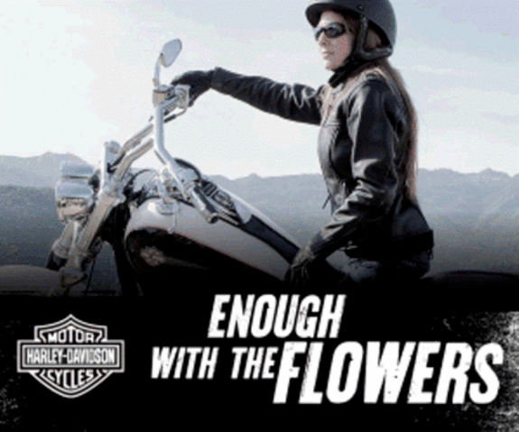 Woman in leather jacket on a Harley Davidson motorcycle with text 'Enough with the flowers'.