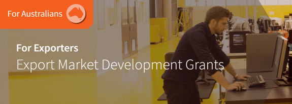 Man working on computer in industrial setting with export grants text overlay