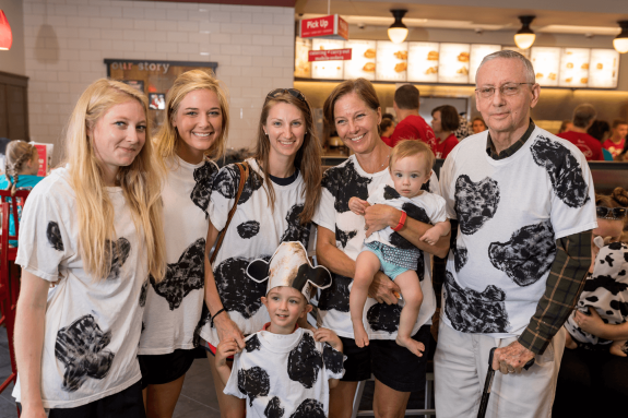 Family wearing cow print shirts posing inside a restaurant.