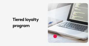 Laptop displaying code next to text 'Tiered loyalty program' on white background.