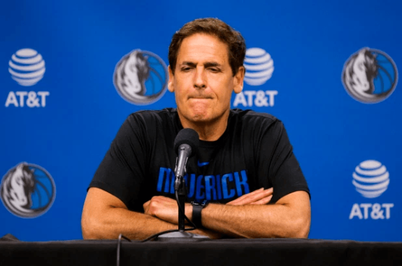 Person speaking at a press conference with a blue background.