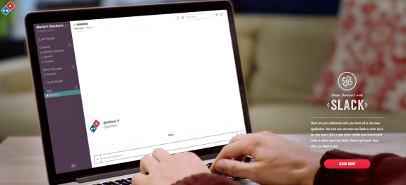 Person using Slack on a laptop to order Domino's pizza.
