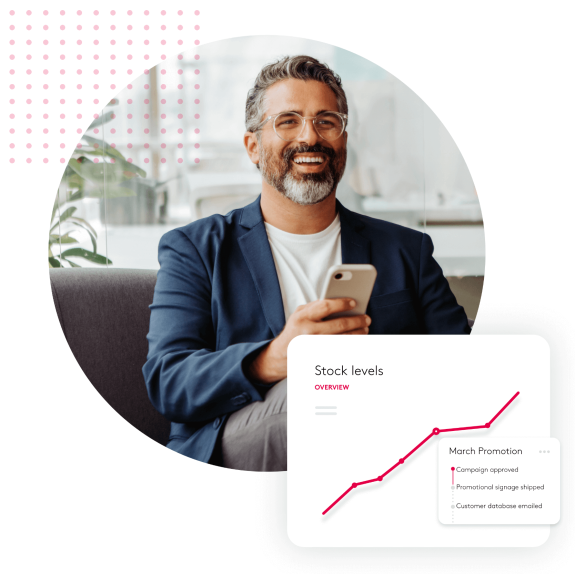 Smiling businessman holding phone with stock graph overlay.