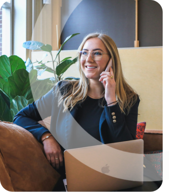 Businesswoman in glasses talking on phone with laptop in office.