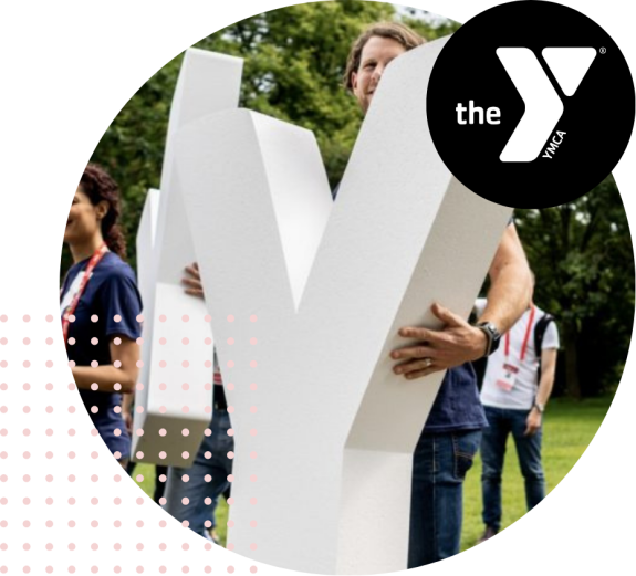 People holding large YMCA letters outdoors at an event.