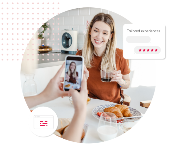 Woman smiling at breakfast table while someone takes a photo with a smartphone.