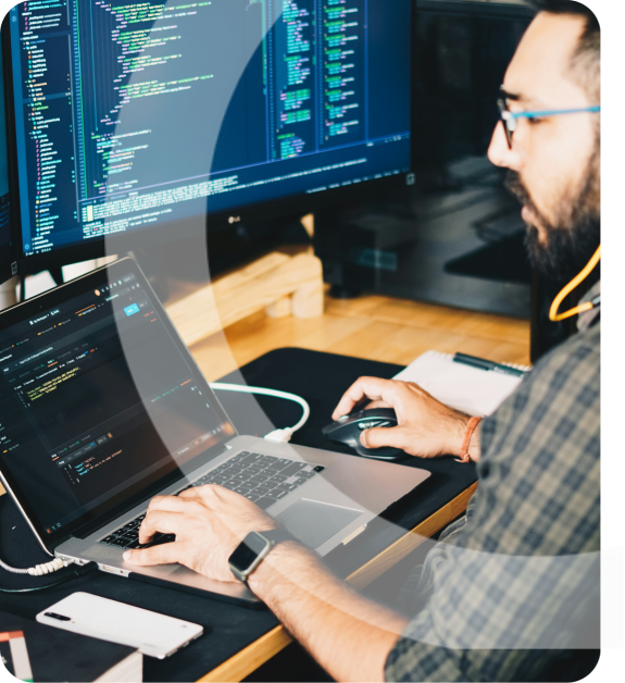 A software developer coding on a laptop with multiple screens displaying code.