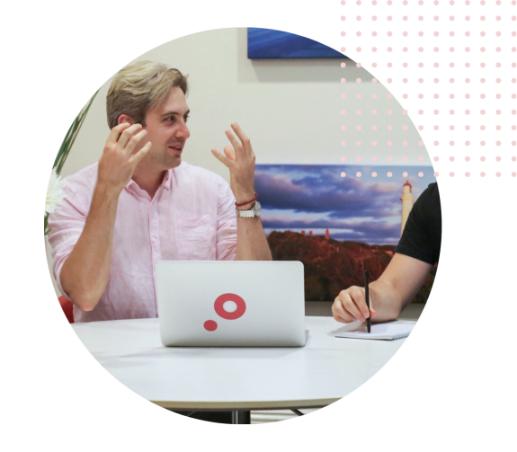 Two people having a discussion at a table with a laptop and notebook.