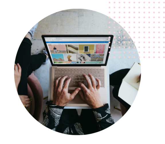 Person using a laptop to browse images during a meeting with others taking notes.
